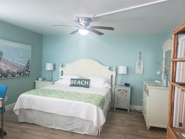 bedroom featuring wood finished floors, baseboards, and a ceiling fan