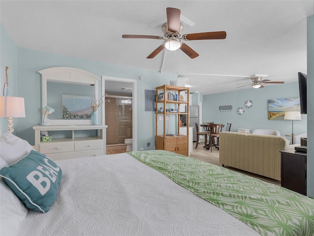 bedroom featuring ensuite bathroom, freestanding refrigerator, ceiling fan, and wood finished floors
