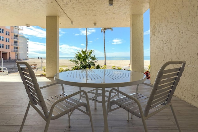 view of patio featuring view of water and beach and a balcony