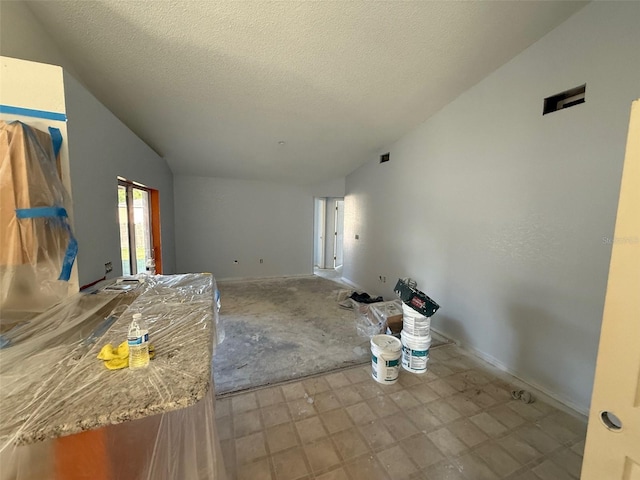 6608 Madeira Ave, Lakeland, FL 33811 - unfurnished living room with vaulted ceiling, a textured ceiling, baseboards, and tile patterned floors