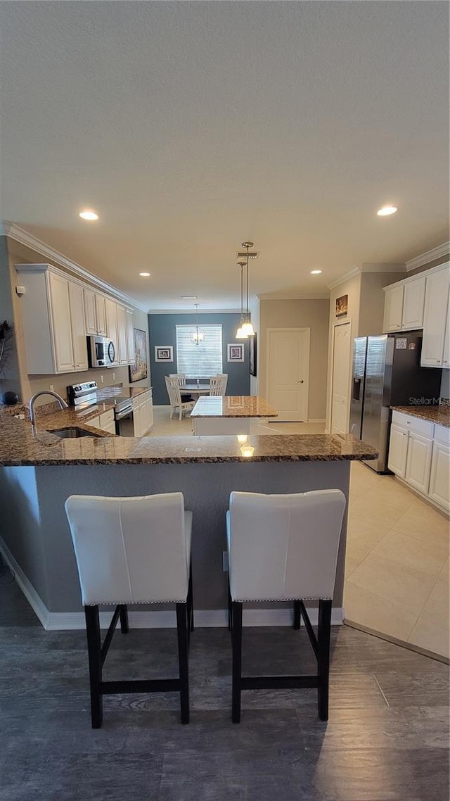 227 Heritage Preserve Run, Bradenton, FL 34212 - kitchen featuring stainless steel appliances, a breakfast bar area, a sink, dark stone countertops, and ornamental molding