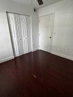 2013 Dixie Belle Dr Unit 2013K, Orlando, FL 32812 - unfurnished bedroom with baseboards, dark wood-type flooring, and a ceiling fan