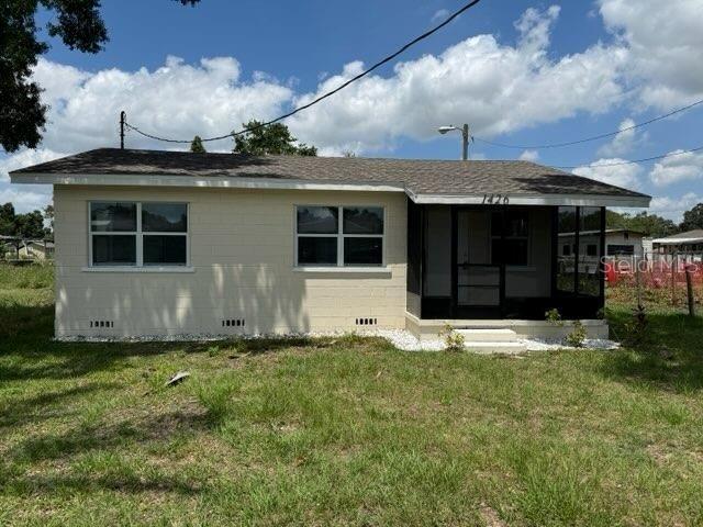 1426 Martin Luther King Jr Ave, Wauchula, FL 33873 - back of property featuring a sunroom, a lawn, and roof with shingles