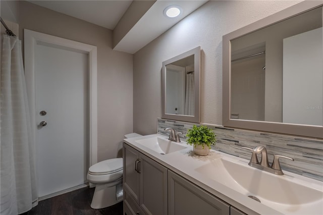 4514 Crichton Ln, Orlando, FL 32806 - bathroom with double vanity, wood finished floors, toilet, curtained shower, and decorative backsplash