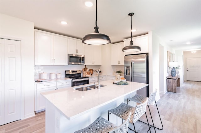 2046 Sunset Preserve Way, Port Charlotte, FL 33953 - kitchen with appliances with stainless steel finishes, a sink, a breakfast bar area, light wood-style floors, and white cabinets