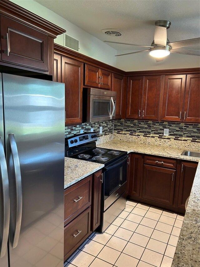 kitchen featuring appliances with stainless steel finishes, light tile patterned floors, tasteful backsplash, light stone counters, and dark brown cabinetry