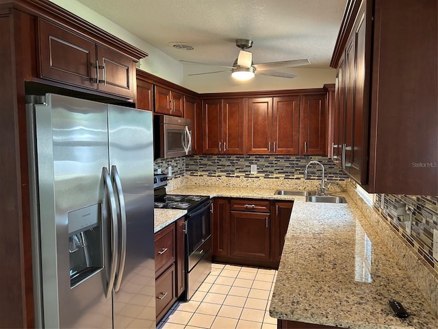 kitchen with appliances with stainless steel finishes, a sink, decorative backsplash, ceiling fan, and light stone countertops