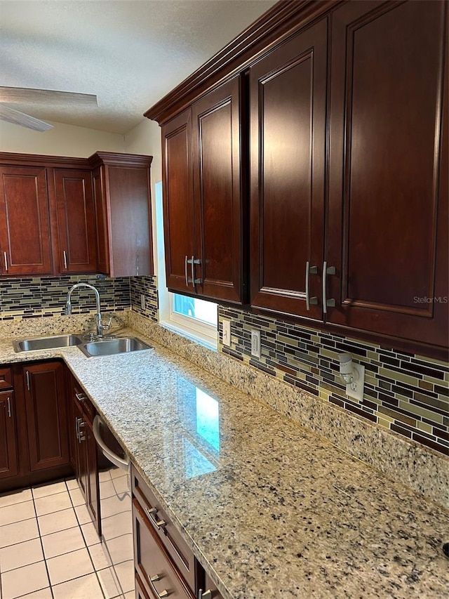 kitchen with a sink, tasteful backsplash, light tile patterned floors, light stone countertops, and a textured ceiling