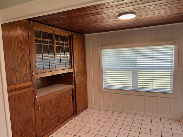 interior space featuring wood ceiling, light tile patterned flooring, and baseboards