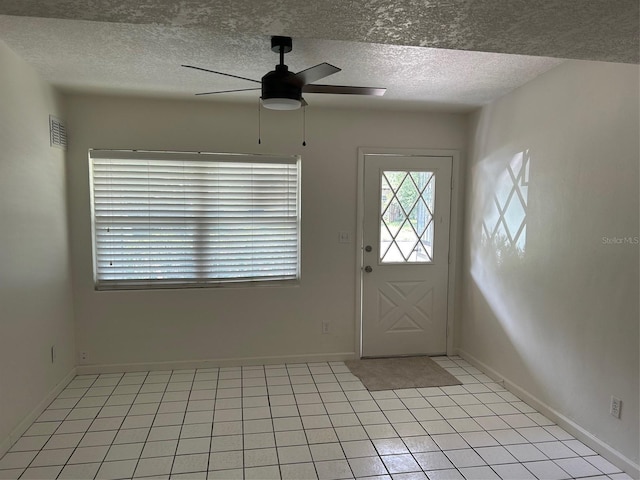 entryway with ceiling fan, a textured ceiling, light tile patterned flooring, and baseboards