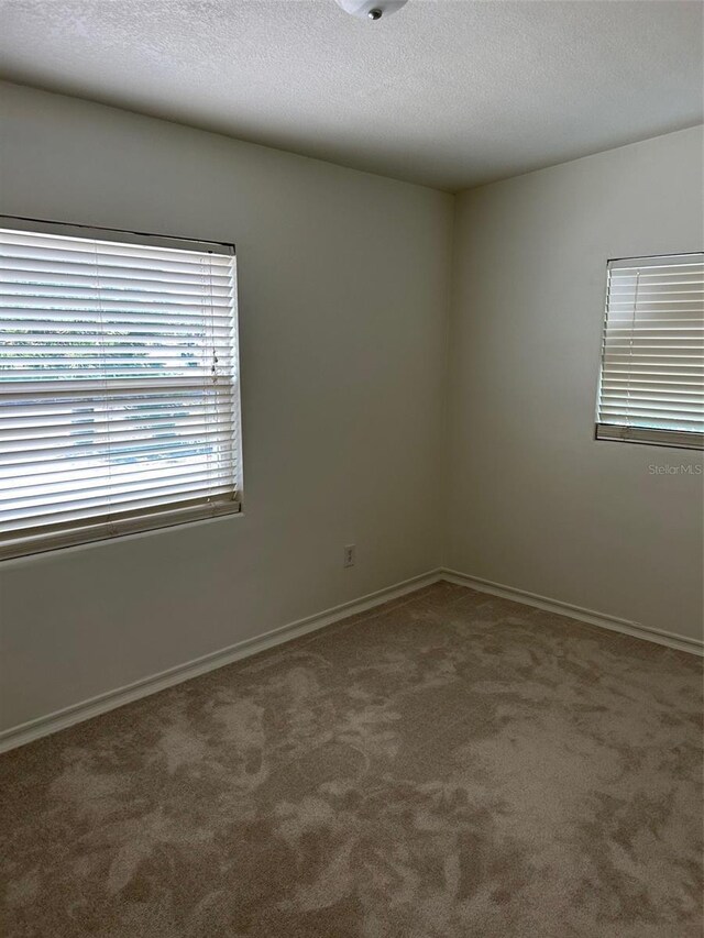 spare room featuring carpet and baseboards