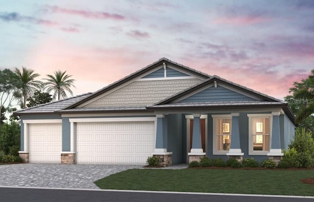 1688 Lugano Cir, North Venice, FL 34275 - view of front of house with decorative driveway, a standing seam roof, an attached garage, a yard, and stone siding