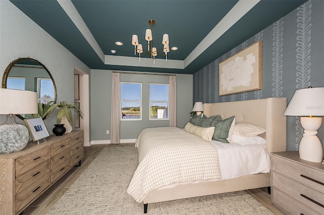 1688 Lugano Cir, North Venice, FL 34275 - bedroom with a chandelier, a tray ceiling, wood finished floors, recessed lighting, and wallpapered walls