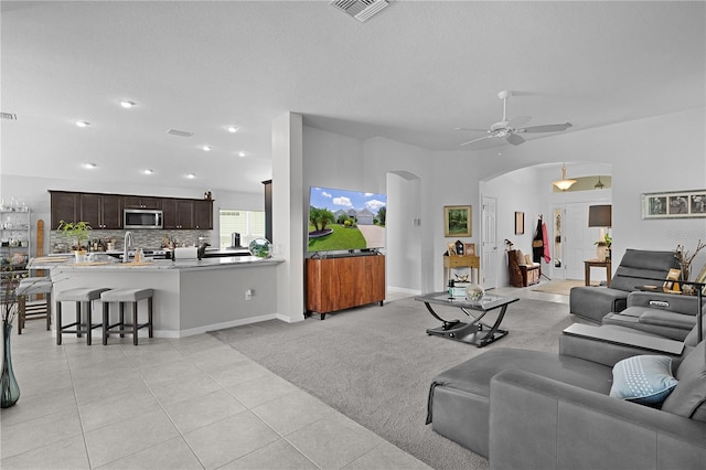924 Figwood Loop, The Villages, FL 32163 - living room featuring arched walkways, a ceiling fan, light tile patterned floors, a textured ceiling, and light carpet