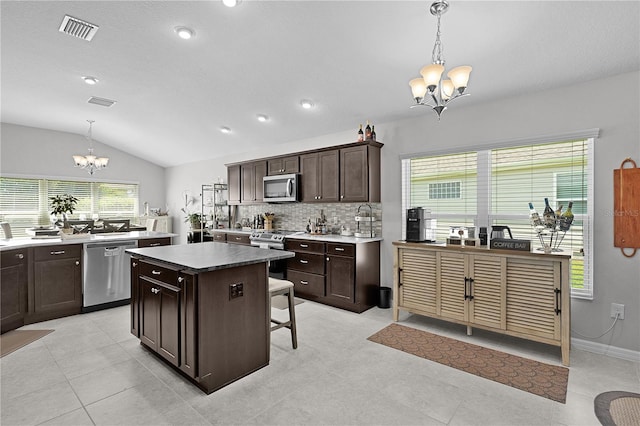 924 Figwood Loop, The Villages, FL 32163 - kitchen with a chandelier, stainless steel appliances, dark brown cabinetry, lofted ceiling, and a kitchen island