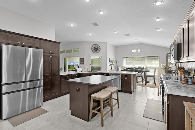 924 Figwood Loop, The Villages, FL 32163 - kitchen featuring stainless steel appliances, a peninsula, dark brown cabinetry, a kitchen island, and lofted ceiling