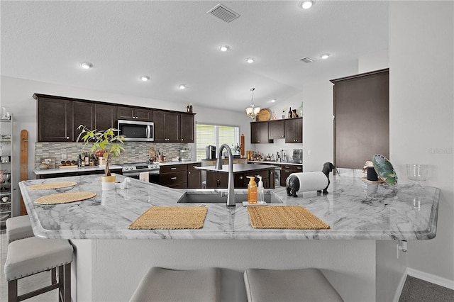 924 Figwood Loop, The Villages, FL 32163 - kitchen with appliances with stainless steel finishes, a sink, dark brown cabinets, a kitchen breakfast bar, and recessed lighting