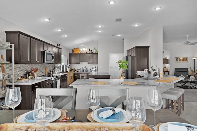 924 Figwood Loop, The Villages, FL 32163 - kitchen featuring stainless steel appliances, a sink, dark brown cabinets, vaulted ceiling, and ceiling fan