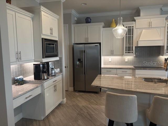 16617 5th Ave E, Bradenton, FL 34212 - kitchen with stainless steel fridge with ice dispenser, built in microwave, custom exhaust hood, white cabinetry, and crown molding