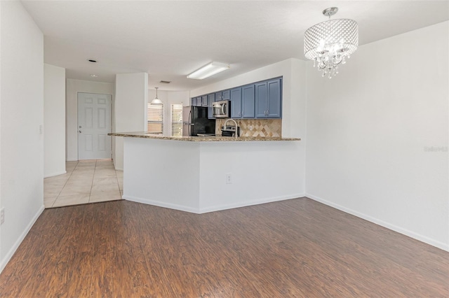 7863 Sugar Bend Dr Unit 7863, Orlando, FL 32819 - kitchen with stainless steel microwave, freestanding refrigerator, light wood finished floors, a chandelier, and blue cabinetry