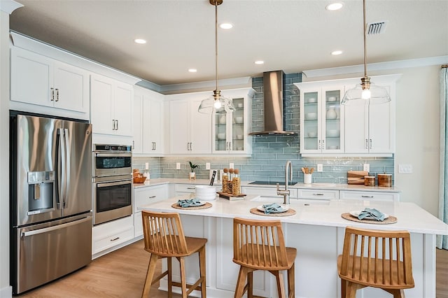 200 Vistera Blvd, North Venice, FL 34275 - kitchen with appliances with stainless steel finishes, wall chimney range hood, decorative backsplash, glass insert cabinets, and light countertops
