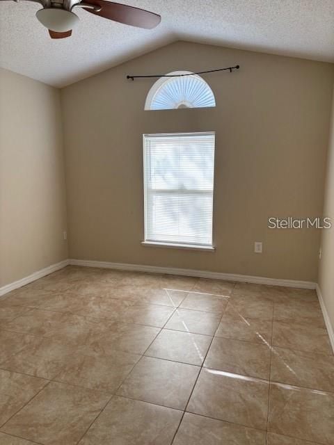 2470 Augusta Way, Kissimmee, FL 34746 - empty room with a textured ceiling, ceiling fan, plenty of natural light, light tile patterned floors, and lofted ceiling