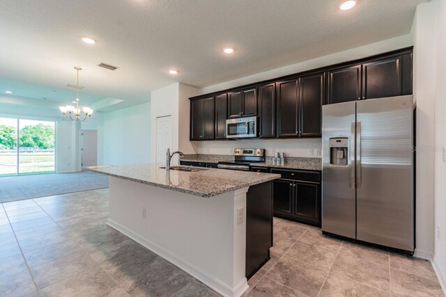 16866 Fiesta Dr, Port Charlotte, FL 33953 - kitchen featuring stainless steel appliances, a chandelier, light stone countertops, an island with sink, and recessed lighting