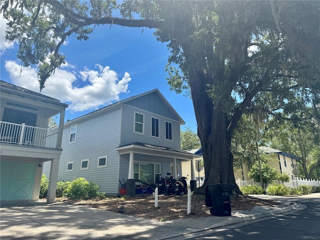 301 NW 8th St, Gainesville, FL 32601 - view of side of home with an attached garage, board and batten siding, concrete driveway, a balcony, and a porch