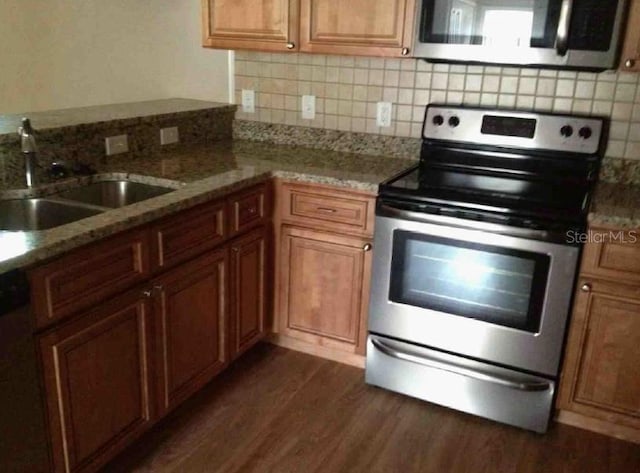 301 NW 8th St, Gainesville, FL 32601 - kitchen with stainless steel appliances, dark wood-type flooring, decorative backsplash, brown cabinets, and light stone countertops