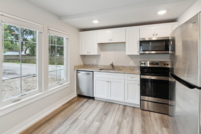 302 NW 7th Ter, Gainesville, FL 32601 - kitchen featuring appliances with stainless steel finishes, white cabinets, light wood-style floors, light stone counters, and recessed lighting