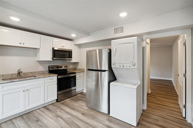 302 NW 7th Ter, Gainesville, FL 32601 - kitchen featuring appliances with stainless steel finishes, stacked washer / dryer, light wood-style floors, white cabinets, and recessed lighting