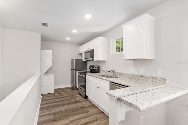 302 NW 7th Ter, Gainesville, FL 32601 - kitchen with stainless steel appliances, light wood finished floors, recessed lighting, white cabinetry, and a peninsula