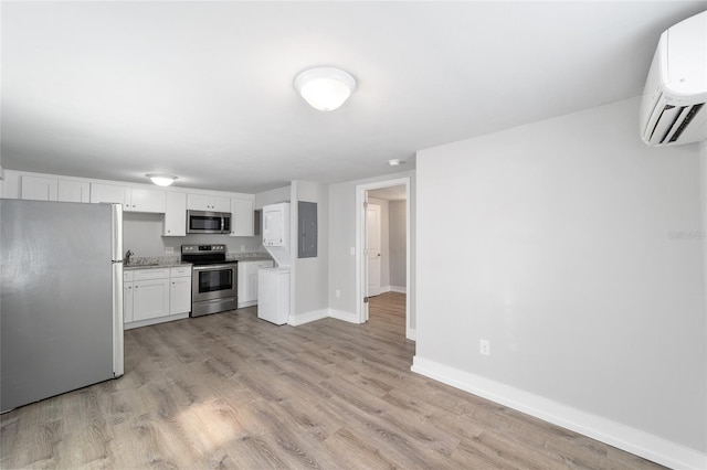 302 NW 7th Ter, Gainesville, FL 32601 - kitchen with appliances with stainless steel finishes, electric panel, a wall mounted AC, and light wood-style floors