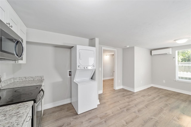 302 NW 7th Ter, Gainesville, FL 32601 - kitchen with stacked washing machine and dryer, electric range oven, stainless steel microwave, an AC wall unit, and light wood finished floors