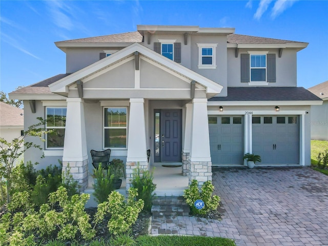 2044 Keystone Pass Blvd, Minneola, FL 34715 - view of front of property featuring stucco siding, an attached garage, decorative driveway, a shingled roof, and covered porch