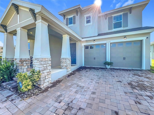 2044 Keystone Pass Blvd, Minneola, FL 34715 - view of front of house featuring stucco siding, an attached garage, stone siding, decorative driveway, and covered porch