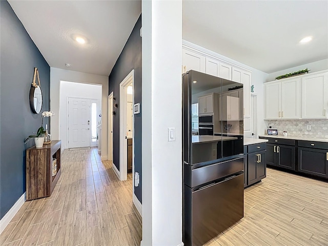 2044 Keystone Pass Blvd, Minneola, FL 34715 - kitchen with white cabinetry, light wood-style flooring, light countertops, freestanding refrigerator, and backsplash