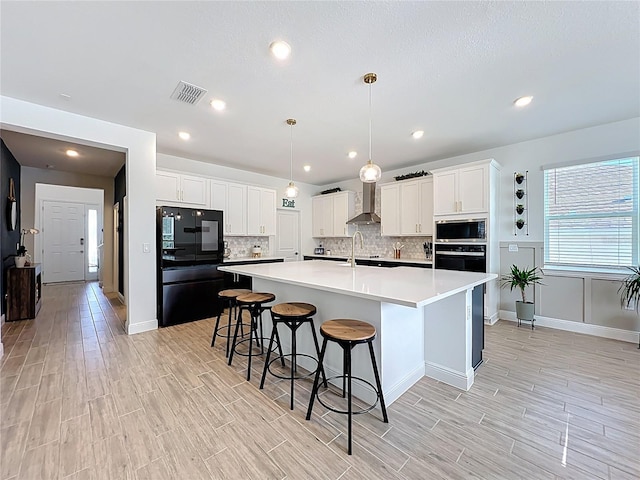 2044 Keystone Pass Blvd, Minneola, FL 34715 - kitchen featuring fridge, stainless steel microwave, wall chimney exhaust hood, light wood finished floors, and tasteful backsplash