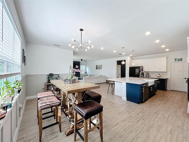 2044 Keystone Pass Blvd, Minneola, FL 34715 - dining room with a chandelier, light wood-type flooring, wainscoting, recessed lighting, and a decorative wall