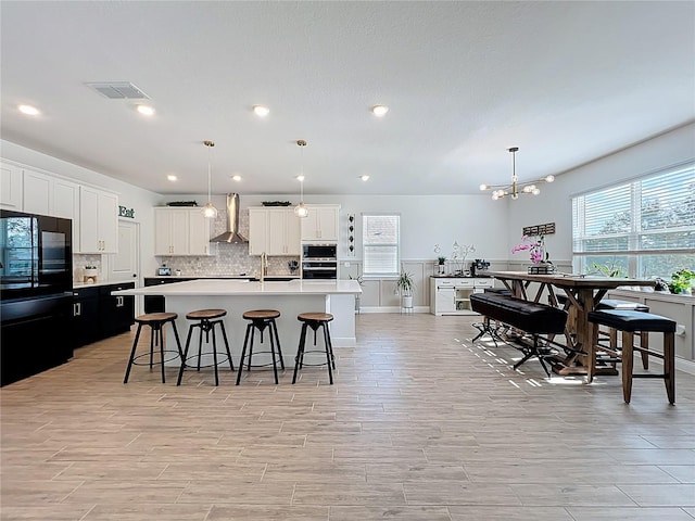 2044 Keystone Pass Blvd, Minneola, FL 34715 - kitchen featuring freestanding refrigerator, wall chimney exhaust hood, healthy amount of natural light, a kitchen island with sink, and recessed lighting