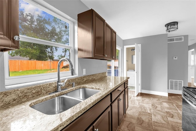 5390 Botany Ct, Orlando, FL 32811 - kitchen with stove, light stone countertops, dark brown cabinetry, and washer / dryer