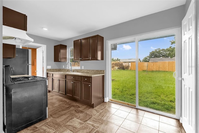 5390 Botany Ct, Orlando, FL 32811 - kitchen with gas stove, dark brown cabinets, freestanding refrigerator, custom range hood, and recessed lighting