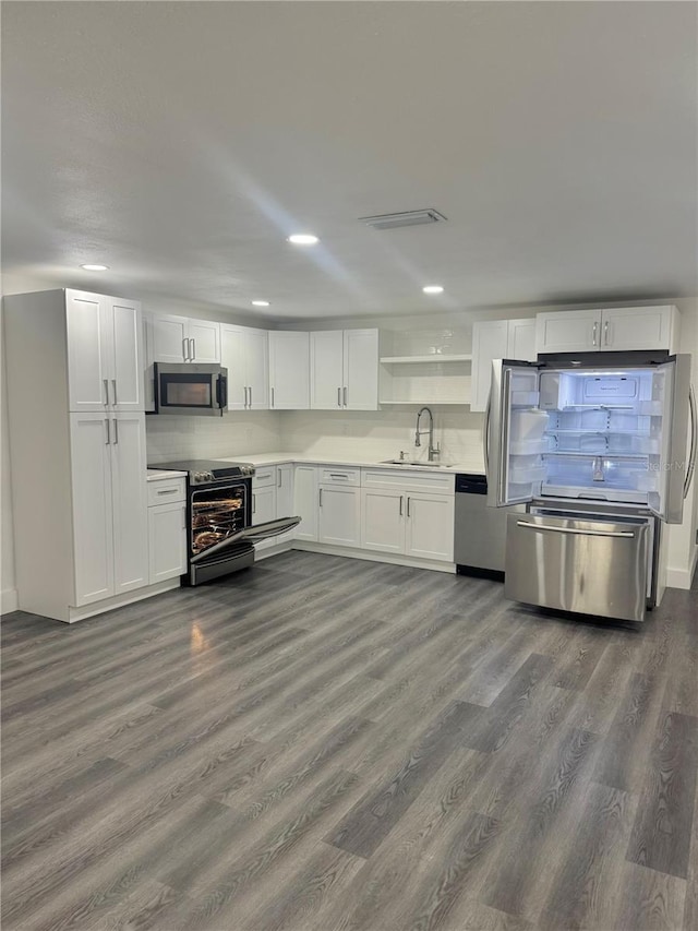 4934 Avery Rd, New Port Richey, FL 34652 - kitchen with stainless steel appliances, dark wood-style flooring, white cabinets, light countertops, and recessed lighting