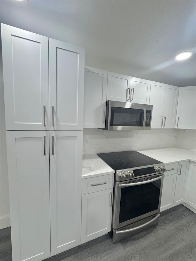 4934 Avery Rd, New Port Richey, FL 34652 - kitchen featuring stainless steel appliances, dark wood-type flooring, white cabinetry, and decorative backsplash