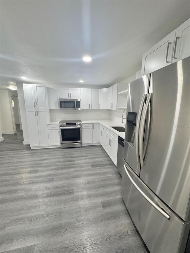 4934 Avery Rd, New Port Richey, FL 34652 - kitchen featuring appliances with stainless steel finishes, open shelves, white cabinets, light wood-type flooring, and light countertops