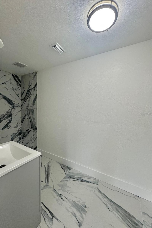 4934 Avery Rd, New Port Richey, FL 34652 - bathroom featuring marble finish floors, a textured ceiling, and vanity