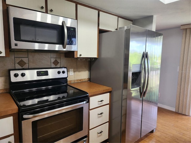 22481 Westchester Blvd Unit A19, Punta Gorda, FL 33980 - kitchen with appliances with stainless steel finishes, tasteful backsplash, light wood-style flooring, and white cabinetry