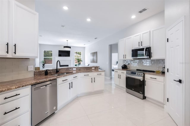 9844 Montclair Cir, Apopka, FL 32703 - kitchen featuring appliances with stainless steel finishes, a peninsula, stone counters, decorative backsplash, and white cabinetry