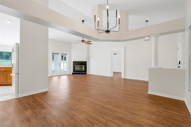 11442 Beggs Ct, Clermont, FL 34711 - unfurnished living room with ceiling fan, light wood-type flooring, a tile fireplace, a high ceiling, and a chandelier