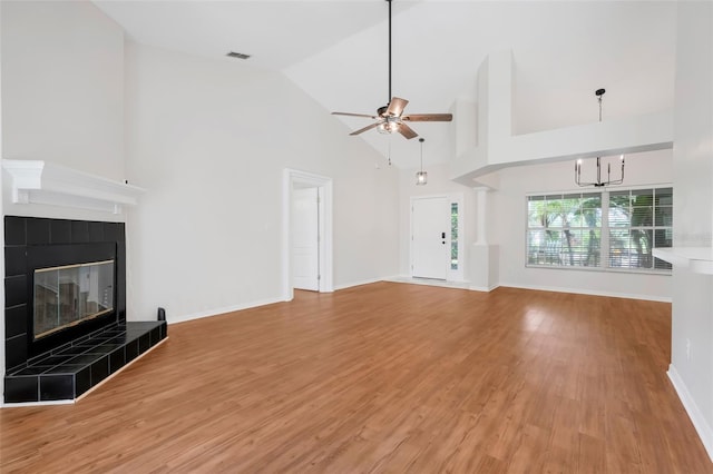 11442 Beggs Ct, Clermont, FL 34711 - unfurnished living room with a tile fireplace, a ceiling fan, a chandelier, light wood-style floors, and high vaulted ceiling